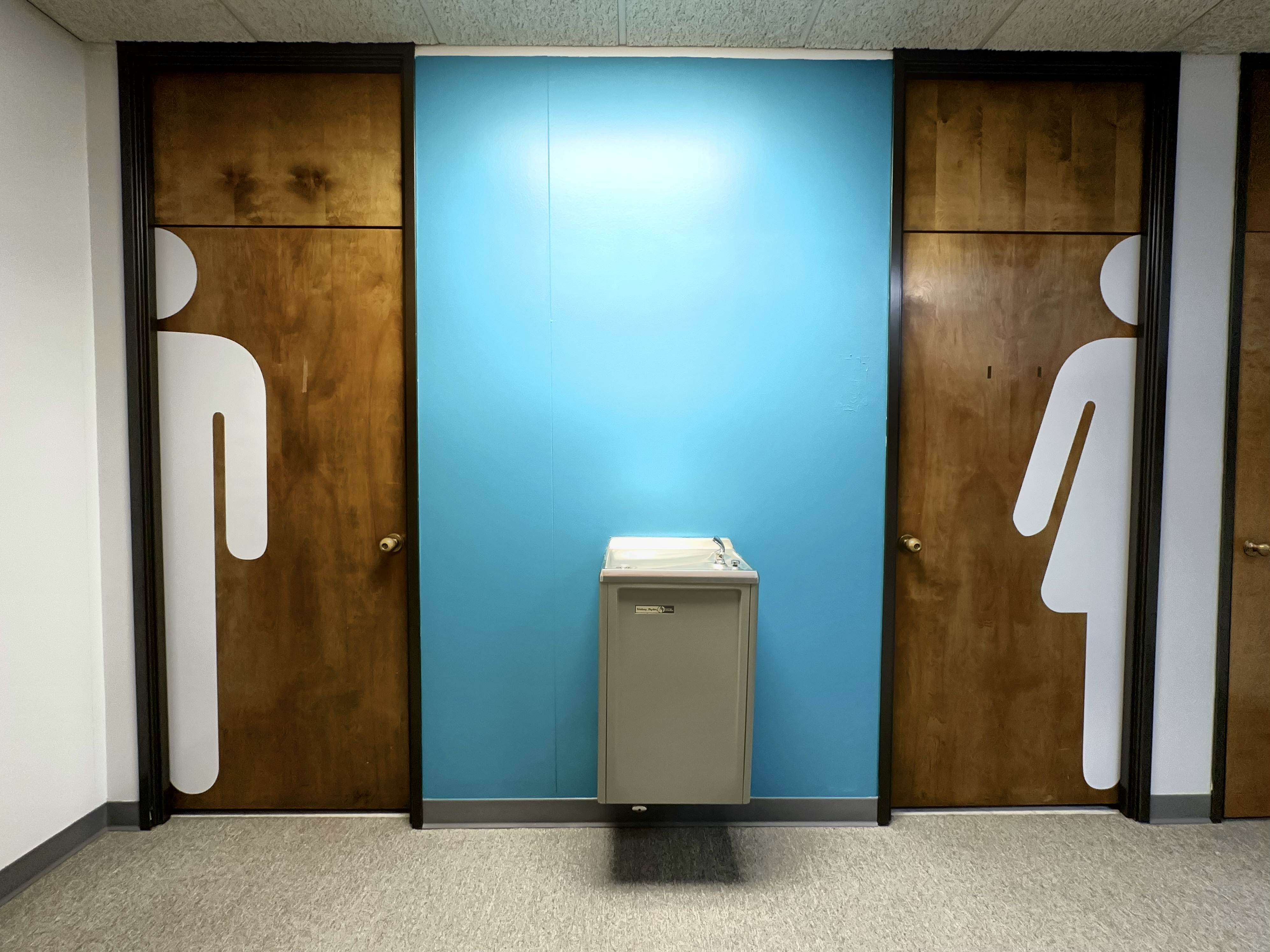 Modern restroom signage on wooden doors with person silhouettes